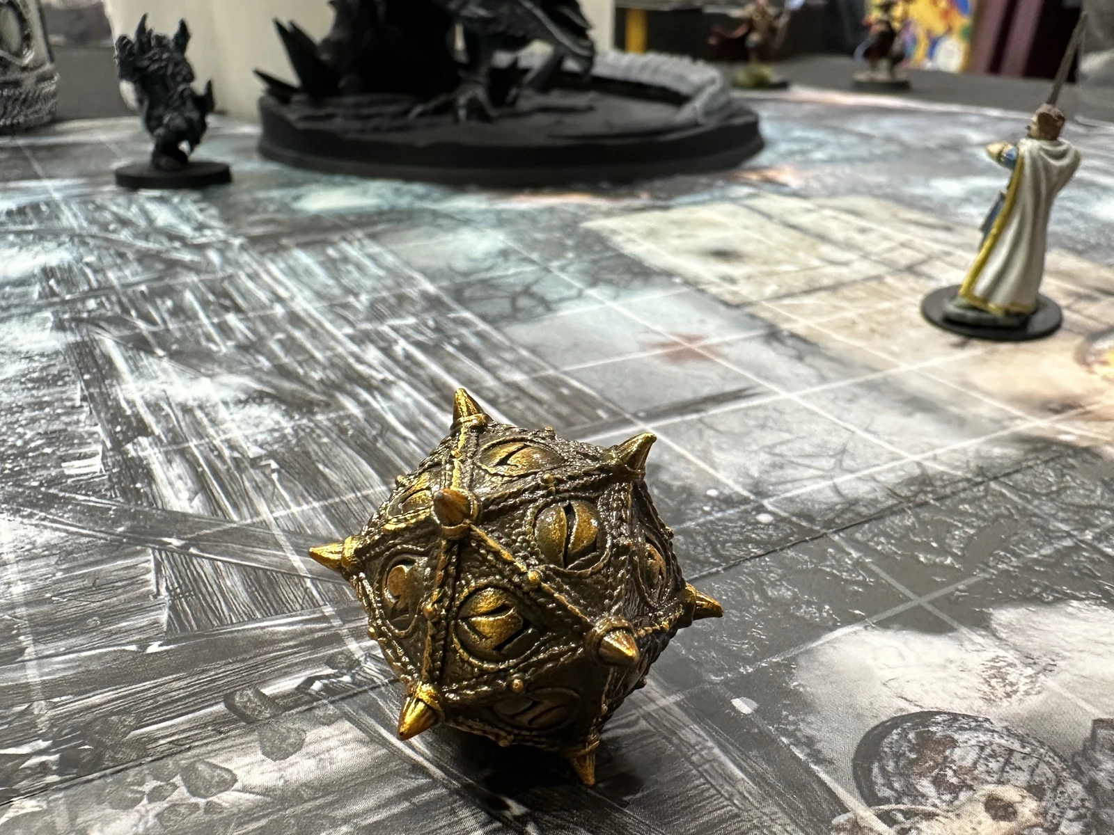 A gold fantasy D20 beside miniatures on the game table